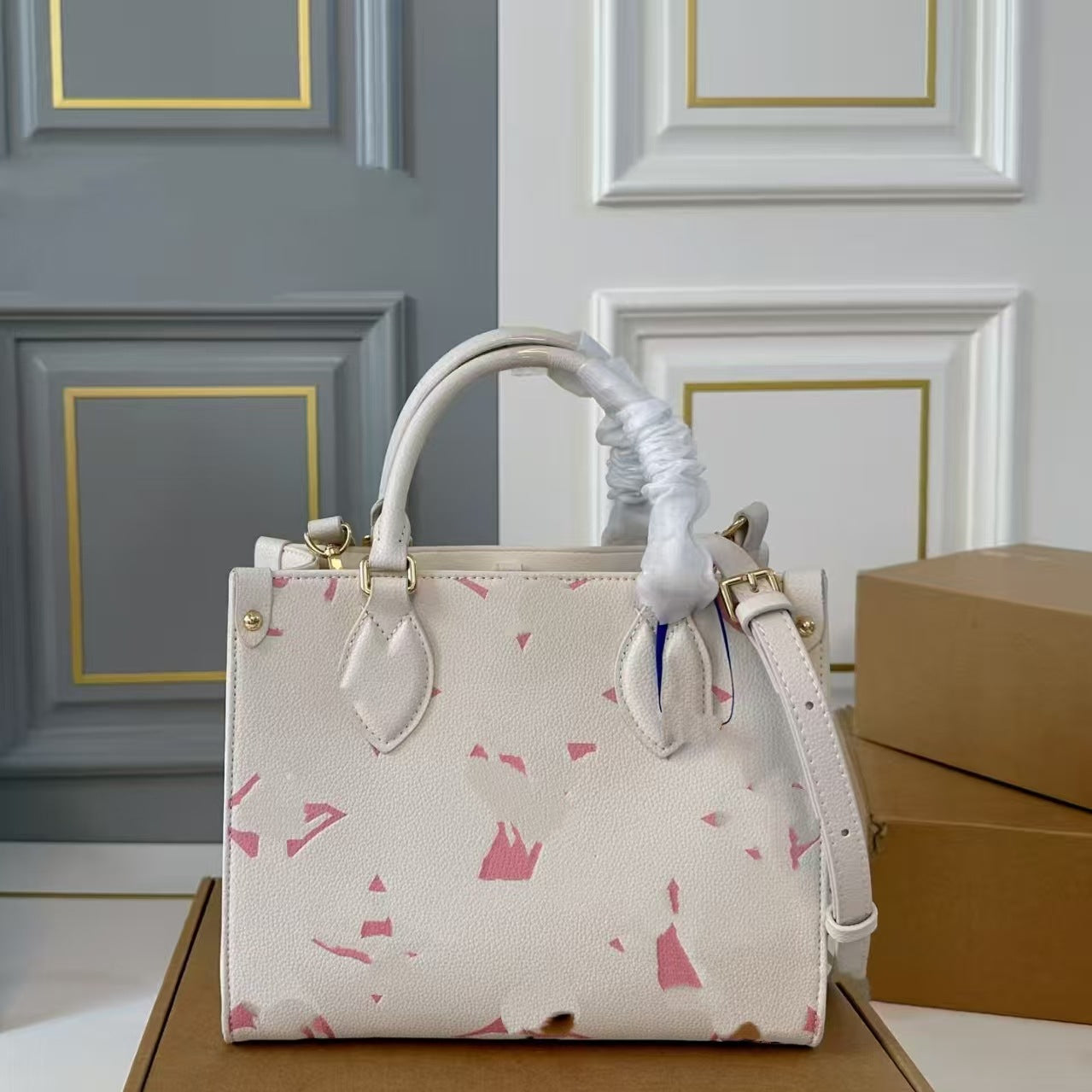 Cream leather tote bag with pink terrazzo print and gold hardware handles.