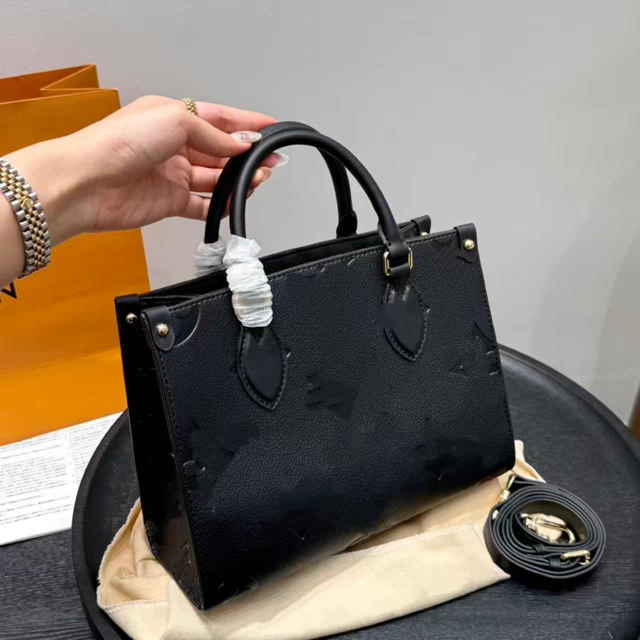 Black Elite Leather Shoulder Tote handbag held by a hand with detachable strap