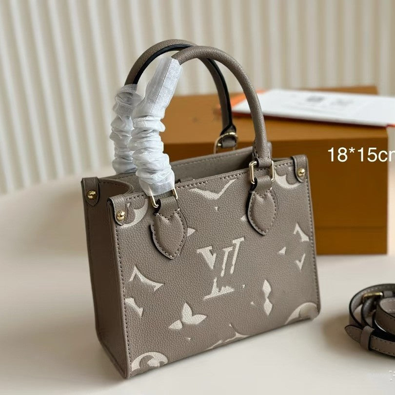 Premium women's grey structured tote bag with large white monogram pattern and gold hardware accents.