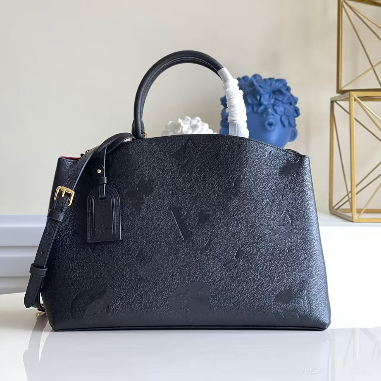 The Urban Montaigne Signature Luxe handbag in black leather with embossed monogram design and gold hardware.