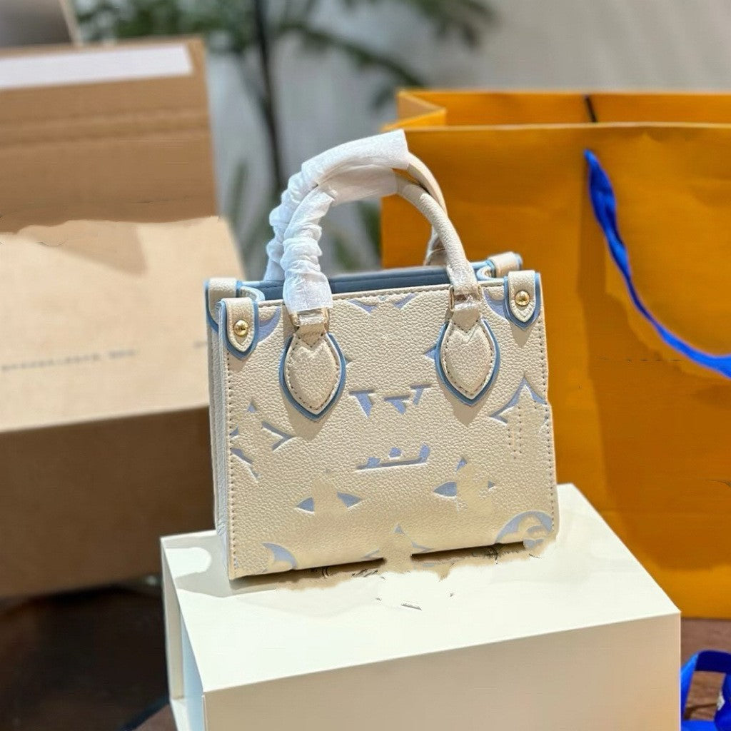 Structured cream leather tote bag with blue accents and monogram pattern, featuring a detachable strap for work and casual use.