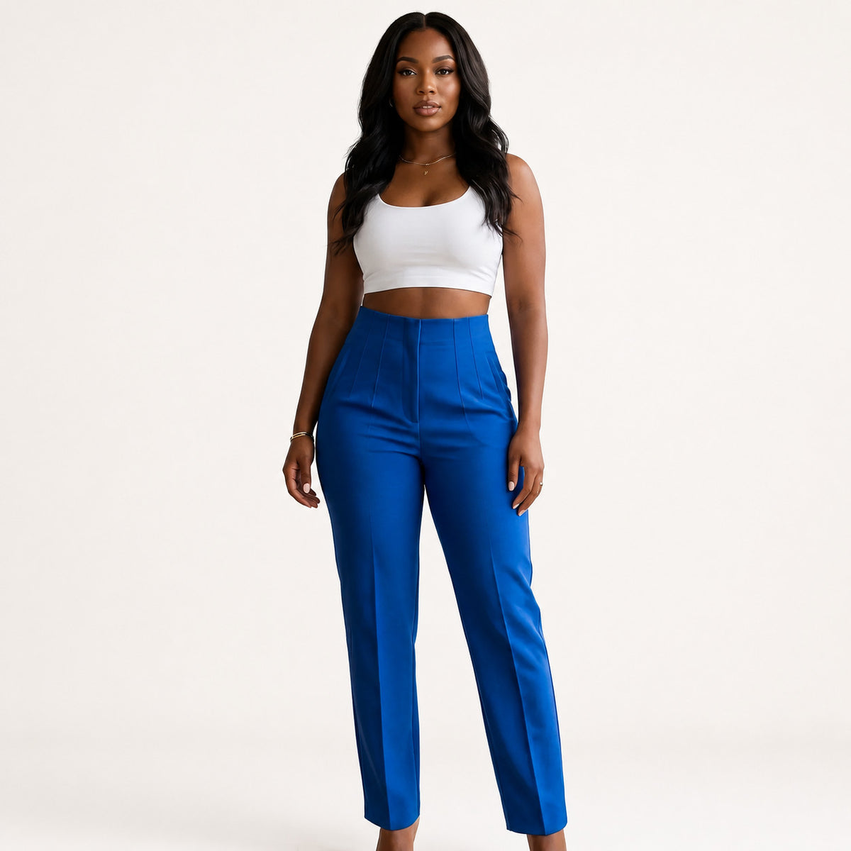 Elegant African American woman wearing sapphire blue pleated high-waist trousers in modern indoor space with soft natural lighting, highlighting relaxed luxury and tailored fit.