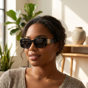 Fashion photoshoot of African American woman wearing retro square cat's eye sunglasses in a modern indoor setting.